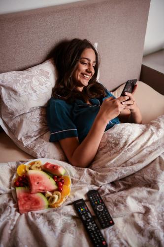 a woman laying on a bed looking at her cell phone at Bungalow Holiday in Pluzine