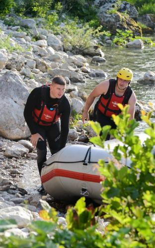 two men in life vests are pushing a raft in a river at Bungalow Holiday in Pluzine