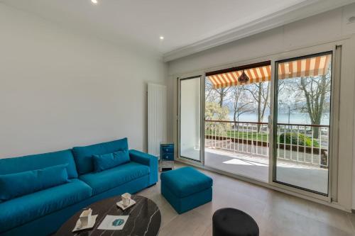 a living room with a blue couch and a large window at Swan Lake - Design apartment facing Lake Annecy in Annecy