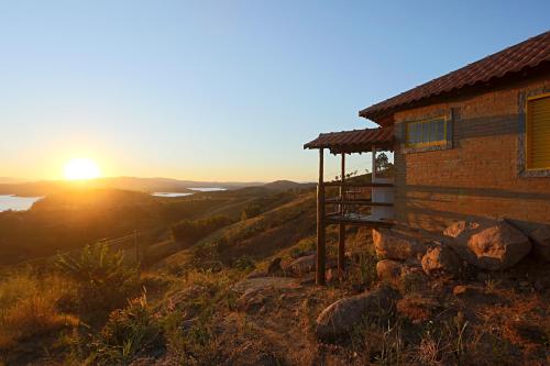 ein Haus auf einem Hügel mit Sonnenuntergang im Hintergrund in der Unterkunft Pousada do Xerife in Caconde