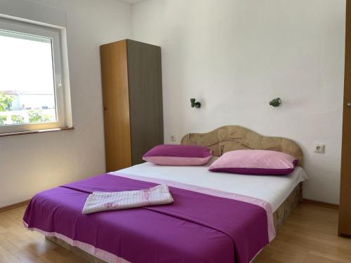 - une chambre dotée d'un grand lit avec des draps violets et d'une fenêtre dans l'établissement Apartments Papic, à Trogir