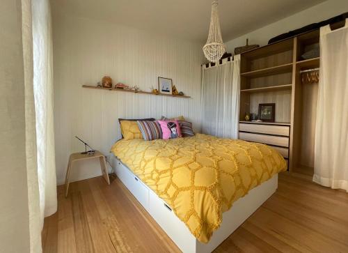 a bedroom with a bed with a yellow comforter at Casita Rica in Glendevie
