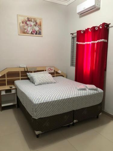 a bedroom with a bed and a red curtain at Hotel Carrão in Sao Paulo