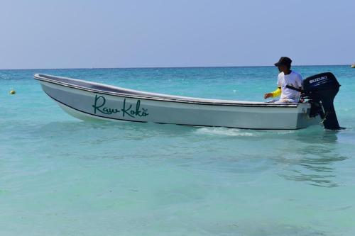 a man standing in a boat in the ocean at Raw KokoMar PosadaNativa in Baru