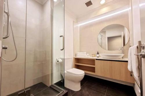 Un baño con inodoro, lavabo y espejo. en Metroview Studio in CBD with Air-con, Pool and Gym, en Auckland