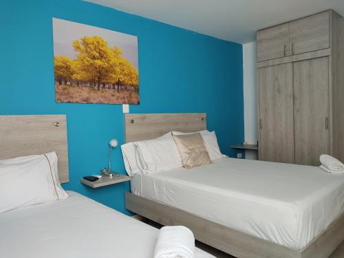 a bedroom with two beds and a blue wall at Escala Hotel in Valledupar