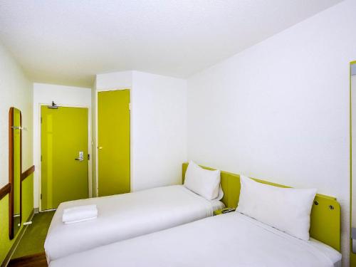 two beds in a room with green and white at ibis Budget - St Peters in Sydney