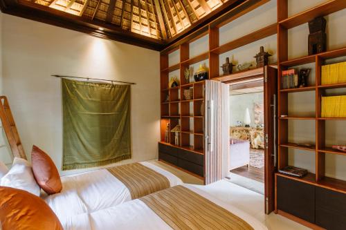 a bedroom with a bed and a large window at Pronoia Beach Resort in Jimbaran