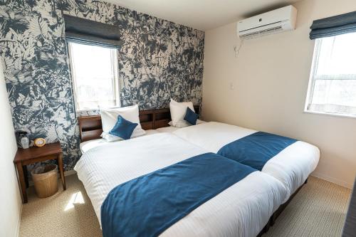 1 dormitorio con 1 cama grande con sábanas azules y blancas en Ecot Sunayama Beach, en Isla Miyako