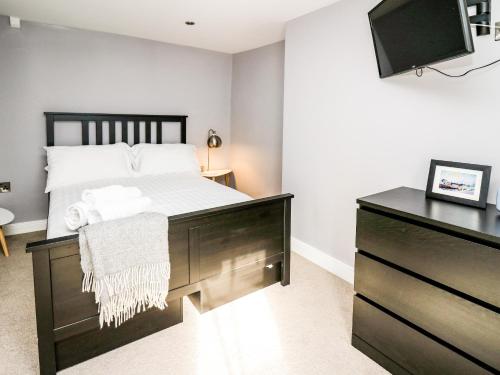 Un dormitorio con una cama y una cómoda con televisión. en Water Street, en Aberaeron