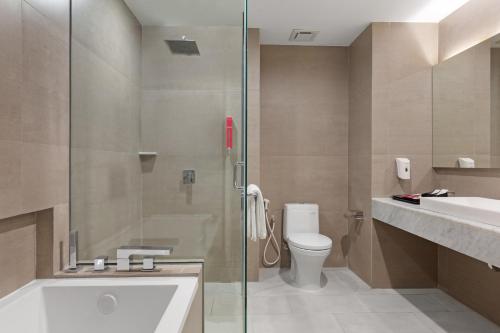 a bathroom with a shower and a toilet and a sink at favehotel Karawang in Karawang