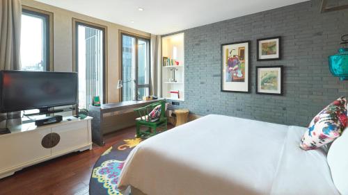 a bedroom with a bed and a flat screen tv at Hotel Indigo Shanghai On The Bund by IHG in Shanghai