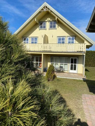 a yellow house with a porch and bushes at Ferienhaus Norway in Wittenbeck