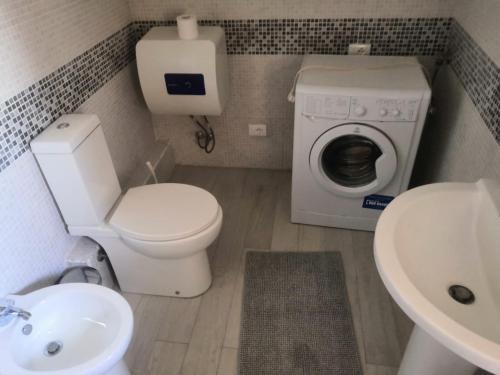 a bathroom with a toilet and a sink and a washing machine at Appartamentino Mansardato in Pedara
