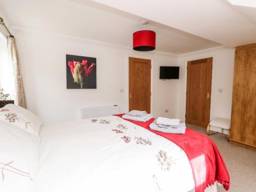 a bedroom with a white bed with a red blanket at Tigh Na Drochit in Garve