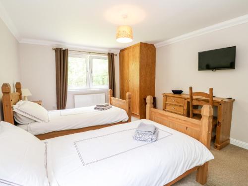 a bedroom with two beds and a tv on the wall at Tigh Na Drochit in Garve