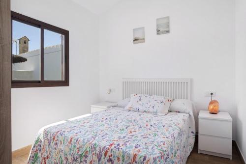 a white bedroom with a bed and a mirror at Casa Jaime in Conil de la Frontera