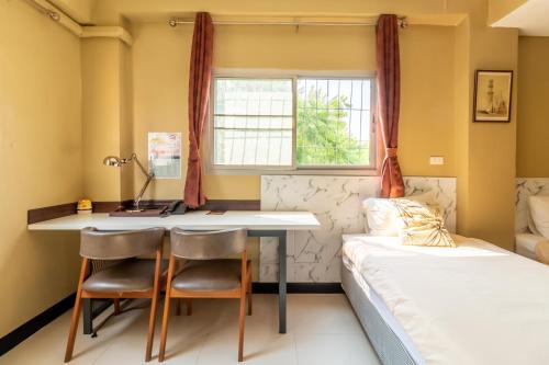 a bedroom with a bed and a desk and a bedskirts at The Palm Hotel in Salaya