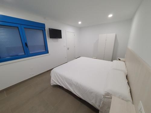 a white bedroom with a bed and a window at A Casa do Lado in Melide