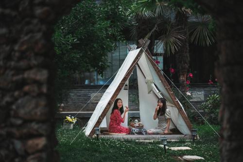 two women sitting in a teepee tent at 阅时 Adonis野生派 Black Bar 森林大院民宿 in Lijiang
