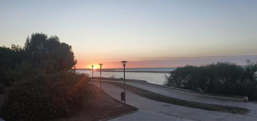 a sunset over the ocean with a sidewalk and street lights at Oceanum Visum Spa Deluxe in El Trocadero