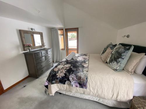a bedroom with a bed with a dresser and a mirror at Glacier Rock Lakeview House in Lake Tekapo