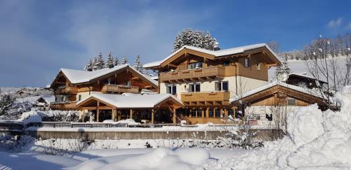une grande maison en bois recouverte de neige dans l'établissement Hotel Sonnenlicht Maria Alm, à Maria Alm