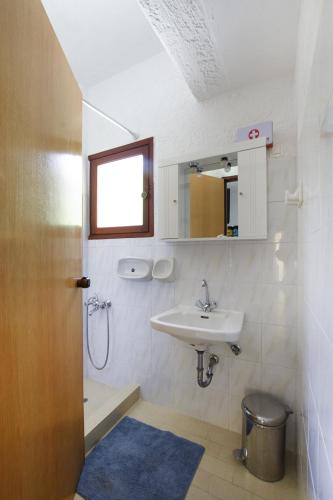 a small bathroom with a sink and a mirror at Galini Apartments in Achlia