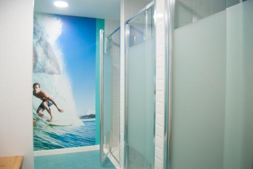 a bathroom with a poster of a woman on a surfboard in the ocean at We Hostel Palma - Albergue Juvenil in Palma de Mallorca