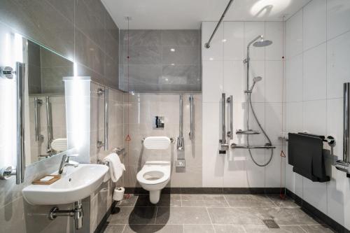 a bathroom with a toilet and a sink and a shower at Radisson Hotel & Suites Amsterdam South in Amstelveen