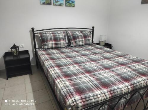 a bed with a plaid comforter and pillows in a bedroom at Melina΄s apartment in Serres