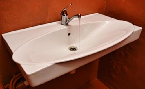 a white sink with a faucet on a wall at Karosta Prison in Liepāja