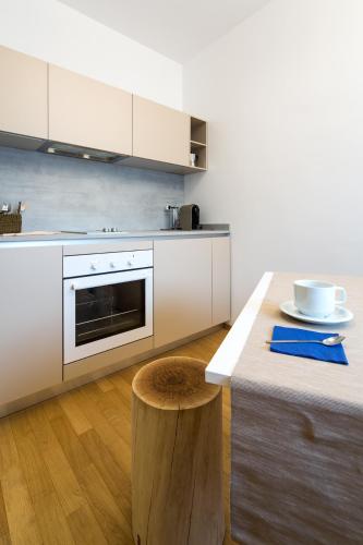a kitchen with white cabinets and a table with a stool at Mercatovecchio Luxury Suites in Udine