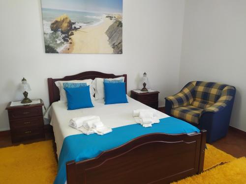 a bedroom with a bed and a chair at Casa S Nicolau 1 Near the beach in Lourinhã