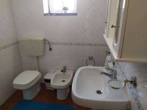 a white bathroom with a toilet and a sink at Casa S Nicolau 1 Near the beach in Lourinhã