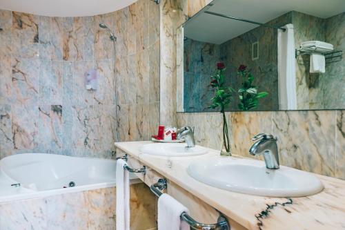 a bathroom with two sinks and a tub and a mirror at Grand Muthu Golf Plaza Hotel & Spa in San Miguel de Abona