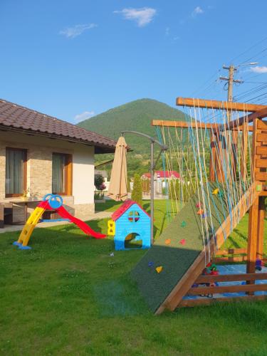 une cour avec une aire de jeux dotée d'un toboggan et d'équipements de jeux dans l'établissement Cuibul Visurilor, à Măieru