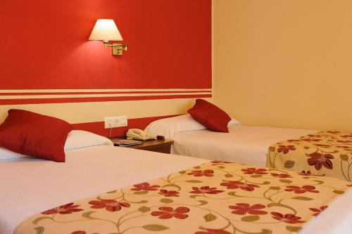 
a hotel room with two beds and two lamps at Hotel Dunas Puerto in El Puerto de Santa María
