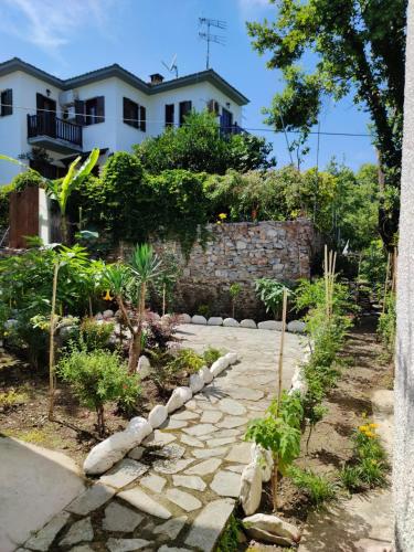 a garden with a stone path in front of a house at Flower house in Chorefto