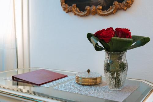 a glass table with a vase with roses and a book at Domus Socolatae Residenza d'Epoca Charming B&B - Adults Only in Follonica