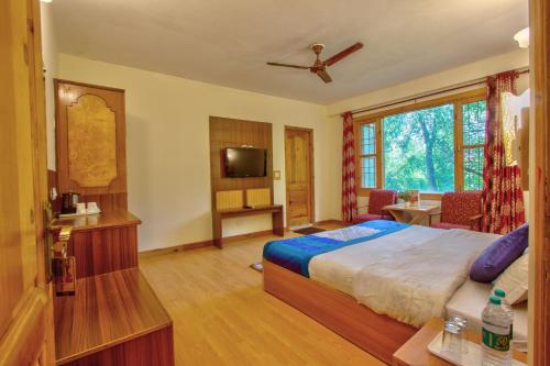 a hotel room with a bed and a television at Woodstock Inn Manali in Manāli