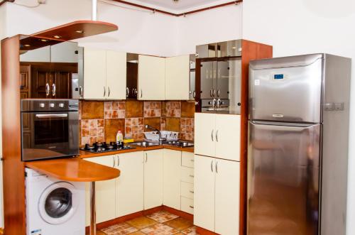 cocina con armarios blancos y nevera de acero inoxidable en Bohemian Apartment - Center of Bucharest, en Bucarest