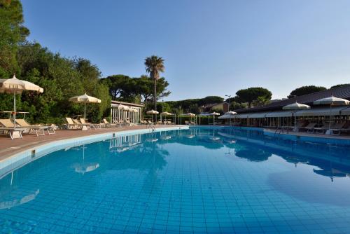 a large swimming pool with chairs and umbrellas at Park Hotel Marinetta - Beach & Spa in Marina di Bibbona