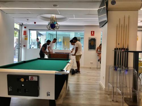a group of people standing around a pool table at We Hostel Palma - Albergue Turístico in Palma de Mallorca