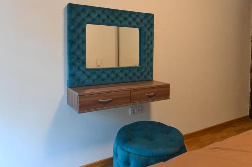 a bedroom with a mirror and a blue chair at Zova Deluxe Apartment in Zlatibor