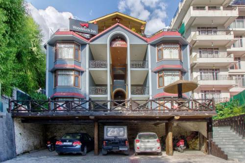 a building with cars parked in front of it at Woodstock Inn Manali in Manāli