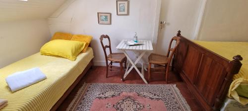 a small room with two beds and a small table at Chambre d'Hôtes Les Jardins de Marie, SCI Charles III in Bernay