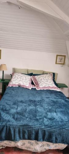 a bed with a blue blanket and pillows on it at Chambre d'Hôtes Les Jardins de Marie, SCI Charles III in Bernay