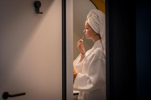 a woman brushing her teeth in front of a mirror at L' Hôtel & Spa Ribeauville- Haut-Koenigsbourg in Ribeauvillé