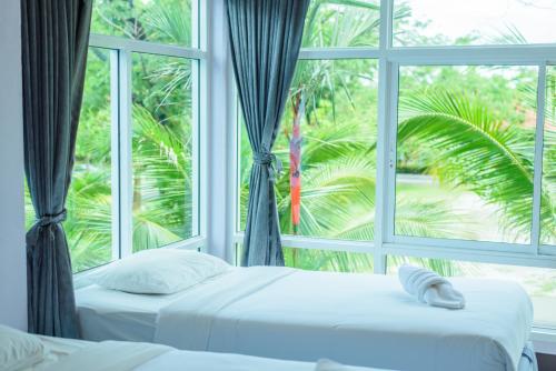 two beds in a room with a large window at หาดตื้น คลื่นสวย รีสอร์ท - Hadtuen Kluensuay Resort in Chao Lao Beach